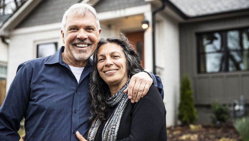 Portrait of senior couple in front of home